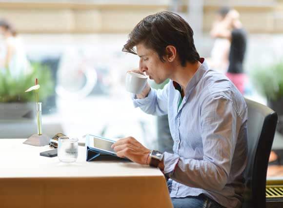 A man sitting at a table with a cup of coffee.